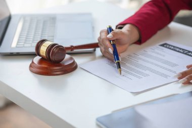 Asyalı kadın avukat ya da hukuk danışmanı bir sözleşme imzalarken avukatlık bürosundaki müvekkil ile olan sözleşme, müvekkili yasal danışman olarak yönlendirecek..