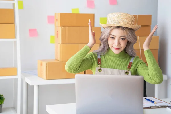 A cute Asian female blogger reviews products and camcorders on a home network, sells online, and presents fashion hats on social media. E-commerce business live stream vlogs new normal concept.