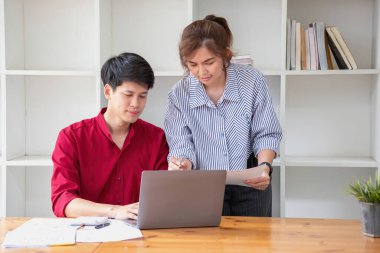 Ofiste dizüstü bilgisayar kullanan neşeli iş adamları. Modern bir çalışma alanında birlikte çalışırken gülümseyen genç girişimciler. İki genç iş adamı bir masada birlikte oturuyorlar..