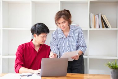 Ofiste dizüstü bilgisayar kullanan neşeli iş adamları. Modern bir çalışma alanında birlikte çalışırken gülümseyen genç girişimciler. İki genç iş adamı bir masada birlikte oturuyorlar..