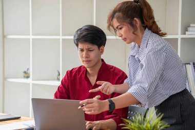 Ofiste dizüstü bilgisayar kullanan neşeli iş adamları. Modern bir çalışma alanında birlikte çalışırken gülümseyen genç girişimciler. İki genç iş adamı bir masada birlikte oturuyorlar..