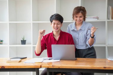 Ofiste dizüstü bilgisayar kullanan neşeli iş adamları. Modern bir çalışma alanında birlikte çalışırken gülümseyen genç girişimciler. İki genç iş adamı bir masada birlikte oturuyorlar..