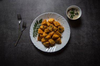 Beyaz bir tabakta servis edilen kızarmış idli parçalarının tepesinden görüntü. Seçici odak.