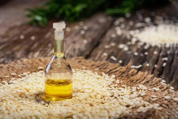 Sesame seeds. Sesame seeds and bottle with oil on a wooden table.
