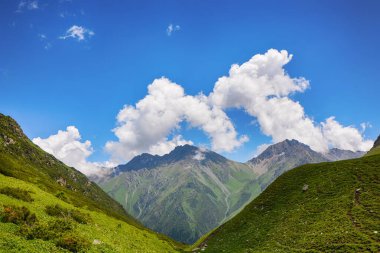 Dağlarda yürüyüş patikaları olan, güzel yeşil dağ çayırları olan, dağların ve bulutların tepesinde huzurlu bir yaz manzarası. Terskey Alatoo Dağları, Tian-Shan, Karakol, Kırgızistan