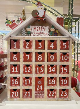 Küçük bir ev şeklinde bir takvim, Aralık ayının günlerinin sayısı küçük çekmecelerde, Noel Baba ve elflerle süslenmiş bir Noel takvimi ve mutlu noeller mesajı, dikey