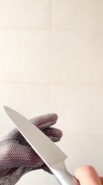 Bir elinde çelik eldiven, diğerinde keskin paslanmaz çelik bıçak, mutfak bıçağıyla kasaplar için koruyucu eldiven, metal eldiven, dikey, dikey, bir parmağıyla mutfak bıçağıyla keserek verimliliği kontrol ediyor.