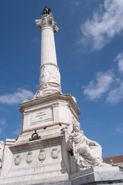 A huge white stone column with a bronze statue of a king of Portugal Pedro IV at the top seen from below, Rossio Square, Lisbon, Portugal, vertical
