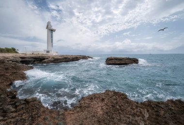 bulutlu bir günde kayalık bir uçurumda modern tarz bir deniz feneri, Alcoceber 'de Faro de Irta, Azahar Coast, Castellon, İspanya, yatay