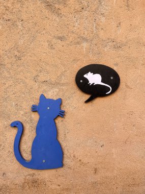 Beton turuncu bir duvar, mavi ahşap bir kedi beyaz bir fare, komik mavi bir kedi ve beton bir duvarda beyaz bir fare, dikey