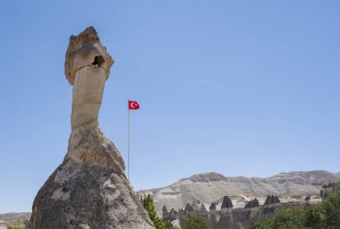 Kapadokya, Anadolu 'daki Goreme açık hava müzesinde büyük bir baca. Rüzgarda dalgalanan bir Türk bayrağı var.