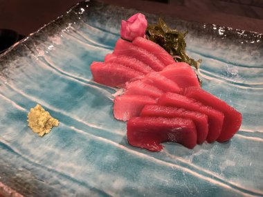 Ton balığının çeşitli yerlerinden gelen kırmızı ton balığı balığı, deniz gibi görünen mavi bir tabakta servis edilir. Deniz yosunu ve yenilebilir çiçeklerle süslenir ve wasabi geleneksel Japon mutfağıdır.