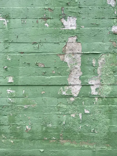 texture of a green painted concrete block wall with paint flaws and chipping, cement wall in bad condition, vertical