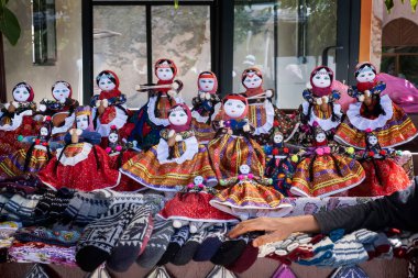 Kapadokya Türkiye 'deki Soganli bebek köyünde tezgaha dayanan zanaatkar kadının eli, tipik kostümler giymiş sokak bez bebek tezgahları.
