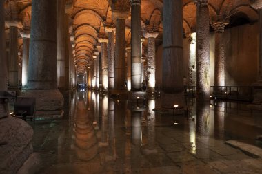 İstanbul 'daki sarnıç bazilikasının içinde, suya yansıyan uzun mermer sütunlarıyla, tanınmayan turistler, yatay köprüler boyunca yürüyorlar.