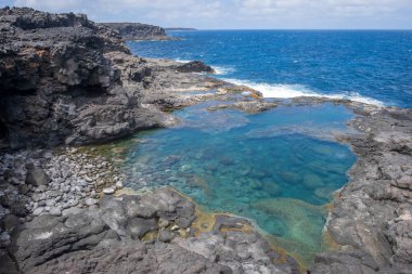 Los Charcones, Lanzarote, İspanya 'daki volkanik bir kayanın üzerinde kristal berrak turkuaz suyu bulunan doğal yüzme havuzu.