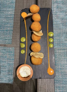 Yukardan görünen tipik kroket tapa, iki sosla süslenmiş, siyah bir tabakta ev yapımı kroket servisi.