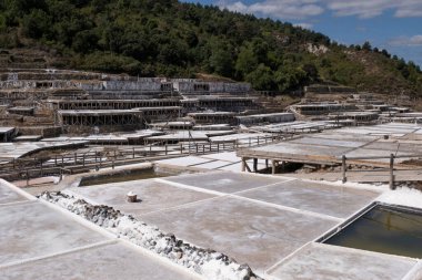 Tuz dolu bir kova dolusu tuz, tuzlu suyun buharlaşmasıyla tuz üretimi, Anana 'nın tuzlama tesisi, yatay olarak tuzlama yapan teraslar veya kristalize edilmiş havuzlar.