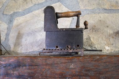 Antika ve kırsal bir ortamda, taş bir arka planda, ahşap bir rafta antika demir levha, yatay.