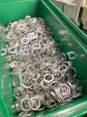Çelik yıkama makinesiyle dolu bir üretim hattında yeşil bir çekmece. Plastik bir kutuda çeşitli paslanmaz çelik yıkayıcılar.