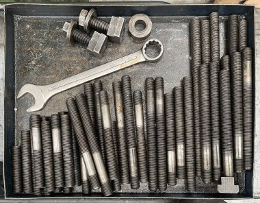 Çelik başlıklı cıvatalı veya çivili metal bir kutu, flanşlar ve fındıklar ve 32 numara açık uçlu anahtar, üst görünüm.