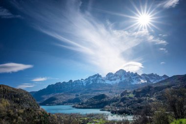 Güneş, kar kaplı arka planda Pena Telera ile Pueyo de Jaca 'da Bubal rezervuarının üzerinde ışıldıyor, Aragonese Pirenesi' ndeki Tena Vadisi 'nde Pyrenean manzarası, yatay