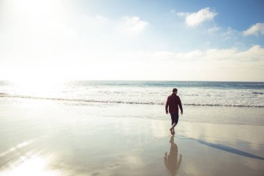 A Man Walks into the Ocean's Blue Waves in the Bright Yellow Light of a Low Hanging Sun