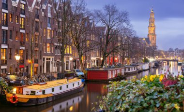 Gün batımında şehrin seddini ve ortaçağ peri evlerinin cephelerini gösteren resimli bir manzara. Amsterdam mı? Hollanda.
