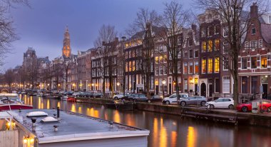 Gün batımında şehrin seddini ve ortaçağ peri evlerinin cephelerini gösteren resimli bir manzara. Amsterdam mı? Hollanda.