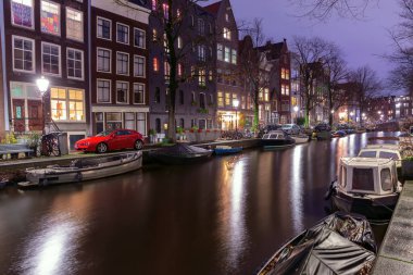 Gün batımında şehrin seddini ve ortaçağ peri evlerinin cephelerini gösteren resimli bir manzara. Amsterdam mı? Hollanda.