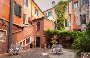 Small old cozy traditional courtyard entwined with greenery at dawn in Venice. Italy.