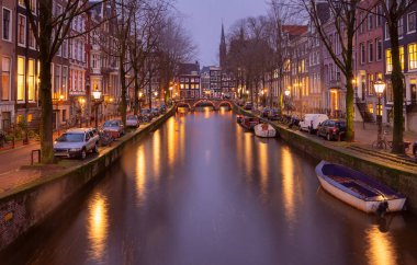 Gün batımında şehrin seddini ve ortaçağ peri evlerinin cephelerini gösteren resimli bir manzara. Amsterdam mı? Hollanda.