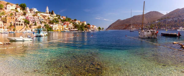 stock image Panoramic view with colorful traditional fishing boats in the bay of Symi island on a bright sunny day. Symi. Greece.