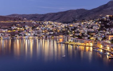 Gün batımında Symi Adası 'ndaki dağ yamaçlarındaki renkli geleneksel evlerin manzarası. Yunanistan.