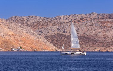 Güneşli bir günde, Symi adasının körfezinde beyaz zevk yatı. Simi. Yunanistan.