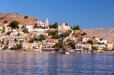 Güneşli bir günde, bir körfezin kıyısındaki Yunan köyü Symi 'de renkli geleneksel evler. Yunanistan.