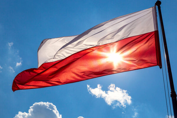 Waving Polish national flag against the blue sky. Poland.