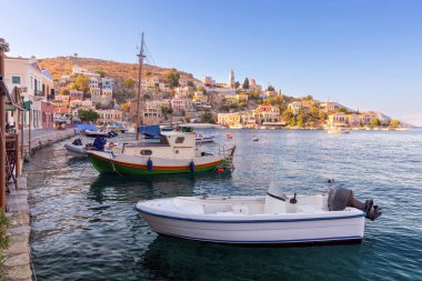 Günbatımında körfezdeki Yunan köyü Symi 'de renkli geleneksel evler ve balıkçı tekneleri. Yunanistan.