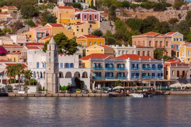 Güneşli bir günde, balıkçı köyü Symi 'deki renkli geleneksel evlerin manzarası. Yunanistan. Dodekanca.