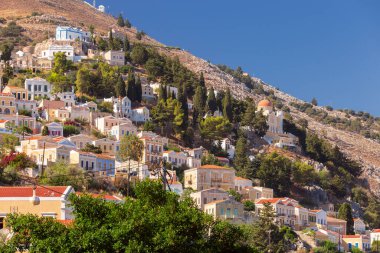 Güneşli bir günde, balıkçı köyü Symi 'deki renkli geleneksel evlerin manzarası. Yunanistan. Dodekanca.