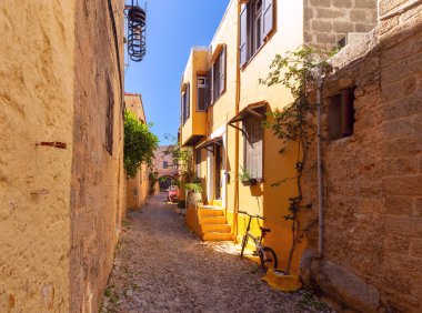 Eski kasabadaki sabah güneşiyle aydınlanan dar bir ortaçağ sokağı. Rodos. Yunanistan.