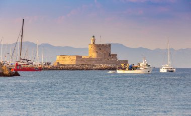 Gün batımında Mandrak limanındaki eski deniz fenerinin manzarası. Rodos. Yunanistan.