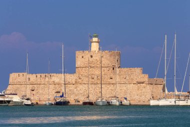 Mandrak Limanı 'ndaki mavi denize karşı güneşli eski deniz fenerinin manzarası. Rodos. Yunanistan.