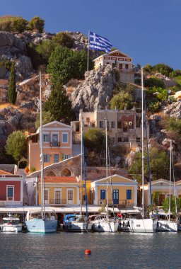 Güneşli bir günde, balıkçı köyü Symi 'de renkli geleneksel evler ve balıkçı tekneleri görülüyor. Yunanistan. Dodekanca.