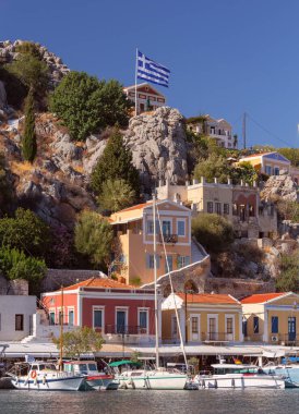 Güneşli bir günde, balıkçı köyü Symi 'de renkli geleneksel evler ve balıkçı tekneleri görülüyor. Yunanistan. Dodekanca.