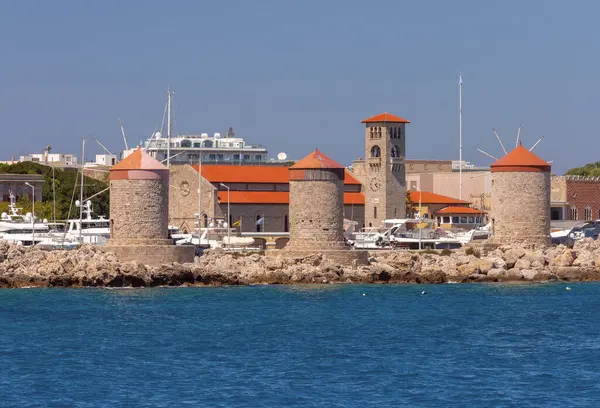 Mandrak Limanı 'ndaki eski taş değirmenlerinin manzarası güneşli bir günde arka planda mavi deniz. Rodos. Yunanistan.