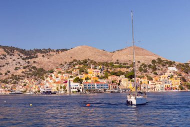 Güneşli bir günde, balıkçı köyü Symi 'de renkli geleneksel evler ve balıkçı tekneleri görülüyor. Yunanistan. Dodekanca.