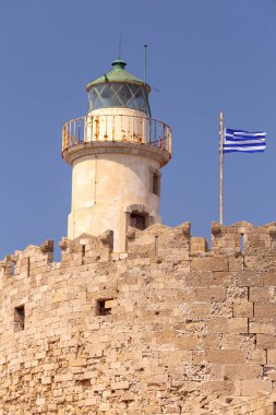 Mandrak Limanı 'ndaki mavi denize karşı güneşli eski deniz fenerinin manzarası. Rodos. Yunanistan.