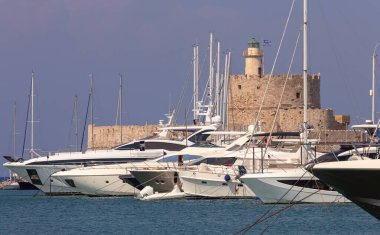 Mandrak Limanı 'ndaki mavi denize karşı güneşli eski deniz fenerinin manzarası. Rodos. Yunanistan.