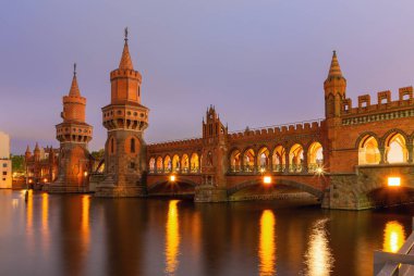 Gün batımında Berlin 'deki Spree nehrinin üzerindeki tarihi Oberbaum köprüsünün manzarası. Almanya.